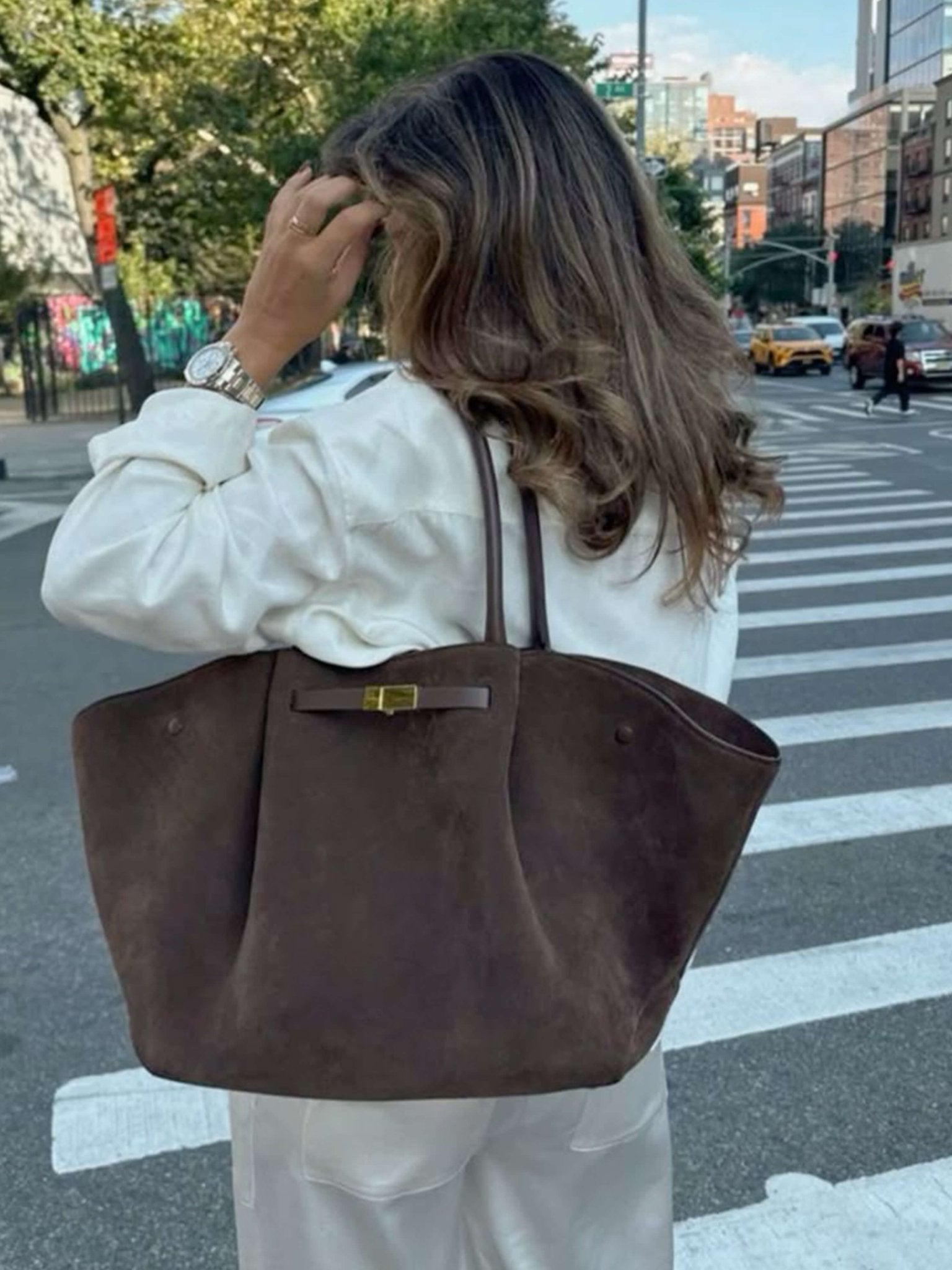 Women’s trapeze-shaped handbag in suede-look material with handles, strap closure, and shoulder strap