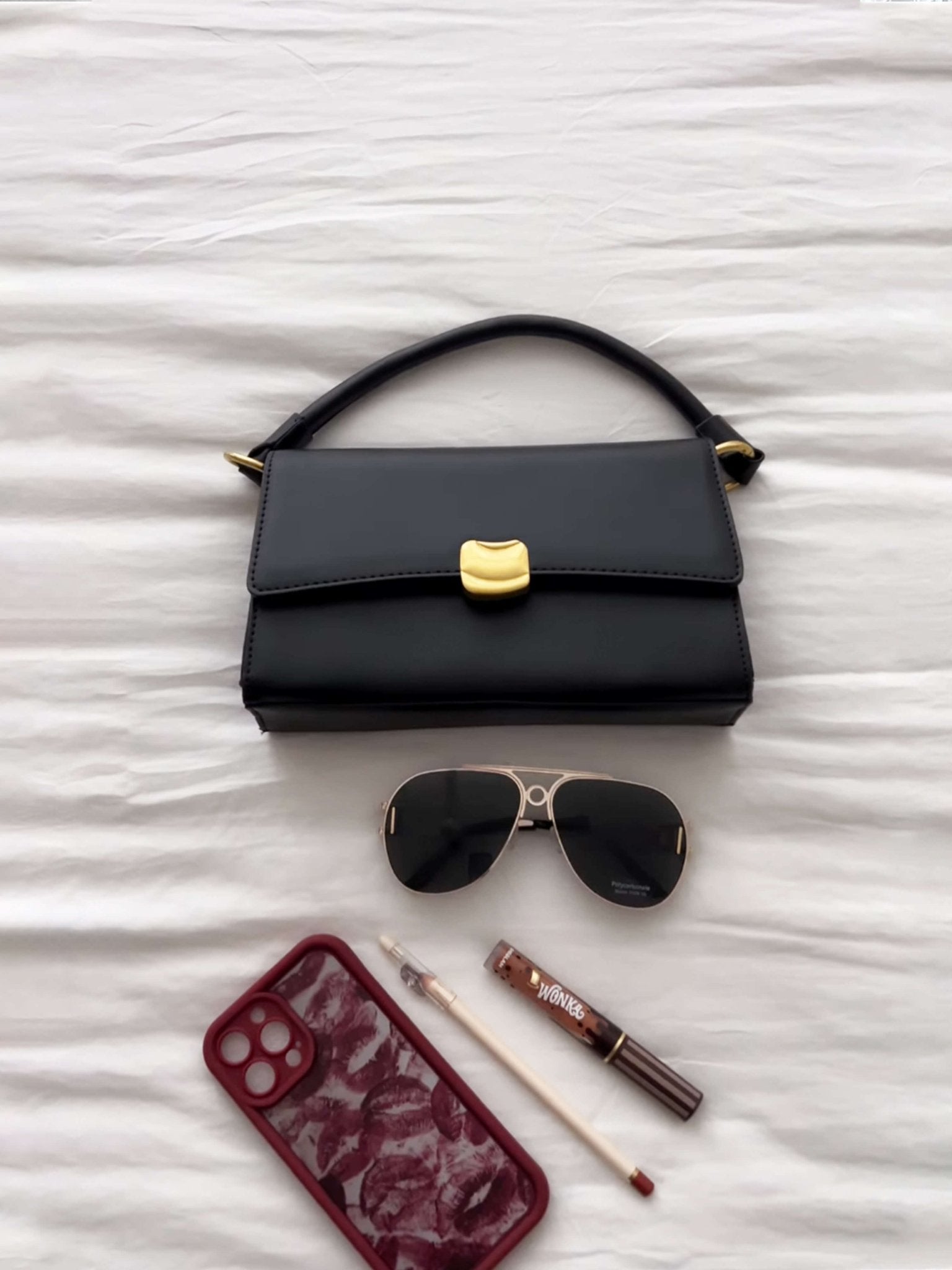 Women’s baguette bag in black faux leather with gold-tone flap clasp